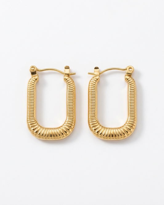 A pair of gold-toned textured hoop earrings with a ribbed, geometric finish, displayed on a clean white background.
